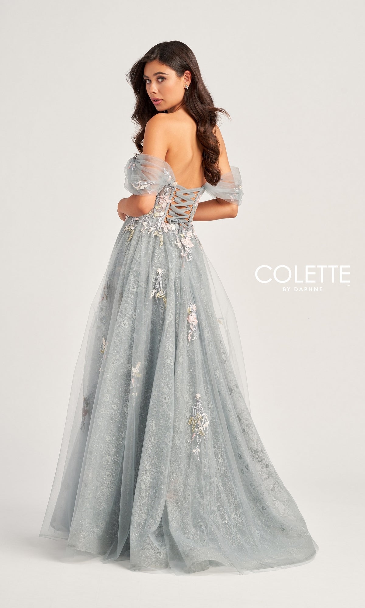 Woman wearing the Colette Off-the-Shoulder Lace Prom Dress CL5169 in light blue, featuring floral embroidery, a lace-up back, and off-the-shoulder design, standing and looking over her shoulder.